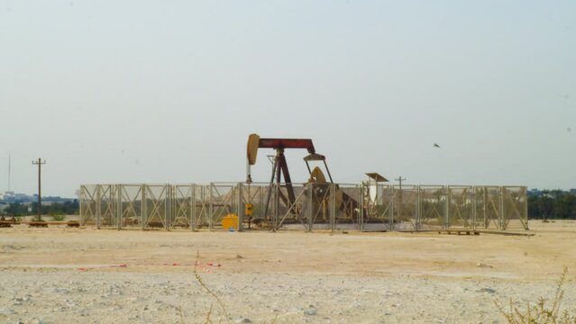 Oil pumps behind a fence in the dessert near the American University of Bahrain
