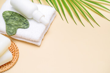 Face massage. Jade green face massager, towel, oil, soap on beige background. Anti age, lifting and...