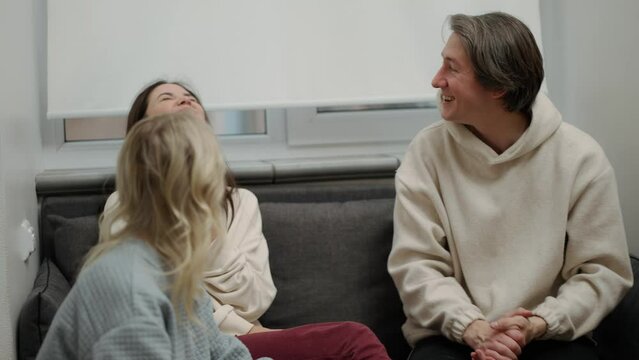 Two women and man having fun together at home while eating pizza