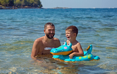 Joyful father and son having fun in water on  beach in Croatia.Summer vacation.Happy lifestyle childhood concept. - 577384141