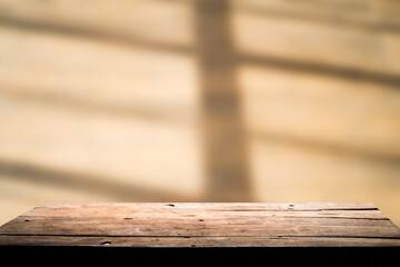 Empty wooden board on table top and blur shadow inside background, mock up for display of goods.