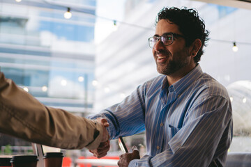 Fototapeta na wymiar Middle-aged Latin man enthusiastically shaking hands with a supplier after closing a deal.