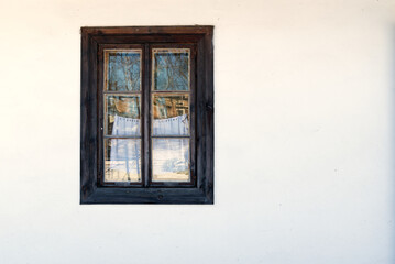 wooden window in a white wall of old farmhouse - view from outside