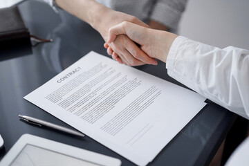 Business people signing contract papers while sitting at the glass table in office, closeup. Partners or lawyers working together at meeting. Teamwork, partnership, success concept.