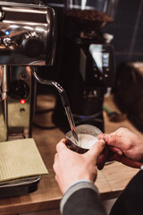 Modern equipment in a coffee shop for preparing coffee drinks - a man brews a cappuccino
