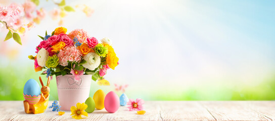 Easter composition with spring flowers in vase, bunny and Easter eggs on wooden table. Easter still life with copy space. Banner