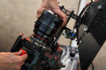 Fototapeta na wymiar caucasian men hands change screw lens on professional movie camera