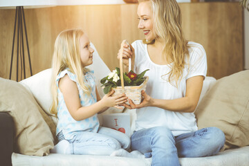 Happy mother day. Child daughter congratulates mom and gives her basket of spring flowers. Family concept