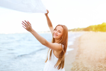 Happy smiling woman in free happiness bliss on ocean beach catching clouds. Portrait of a...