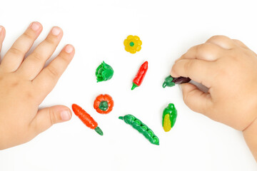 Baby hands playing with Creative plasticine handmade vegetables.Toddler development.