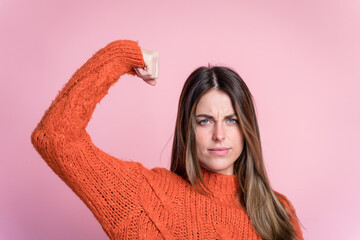 Young woman in sweater doing a strong woman gesture
