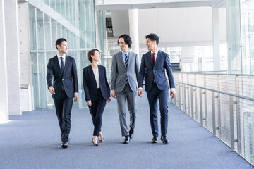 歩くスーツを着た日本人男女