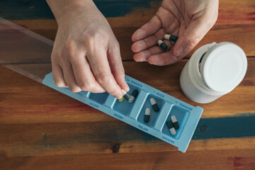 Woman hand taking pill, vitamin from case, holder. Health care and treatment concept