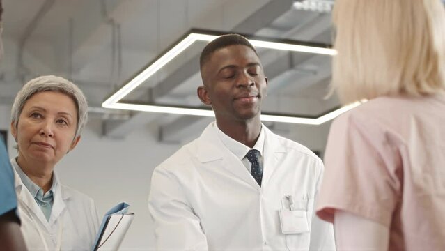 Tilt Up Shot Of Team Of Diverse Doctors With Nurses Shaking Hands While Greeting Each Other At HospitalTilt Up Shot Of Team Of Diverse Doctors With Nurses Shaking Hands While Greeting Each Other At Ho