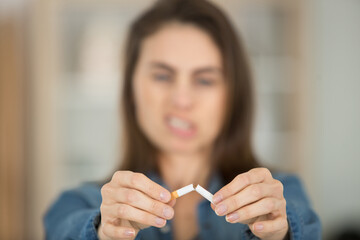 serious woman symbolically breaks a cigarette in half