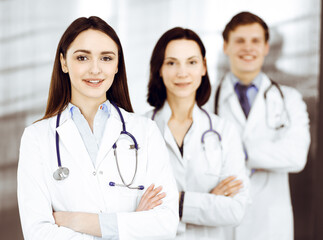 Group of young professional doctors is standing as a team with arms crossed in a hospital office and is ready to help patients