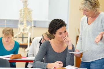 teacher holding paper and questioning student in anatomy class
