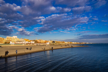 Obraz premium February 12, 2023 - Ostia, Rome, Italy. The sea of Ostia, on the Roman coast, on a winter Sunday. People enjoy the public holiday by walking on the beach in the open air in the evening.