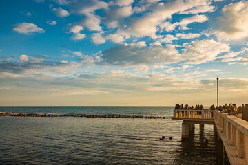 Fototapeta na wymiar February 12, 2023 - Ostia, Rome, Italy. The sea of Ostia, on the Roman coast, on a winter Sunday. People enjoy the holiday walking on the pier in the open air in the evening.