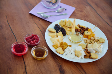 plate with nuts, cheese and honey on table