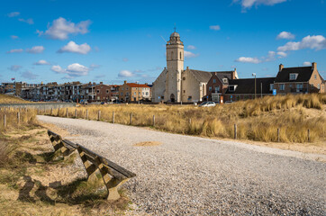 Dutch seaside resort Katwijk aan Zee, church seen from the pedestrian path with benches along sand...