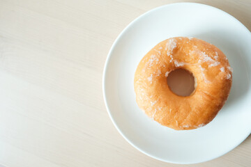 Sweet delicious glazed donut on white plate.