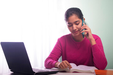 TEENAGER talking on a mobile phone  while ATTENDING ONLINE CLASS