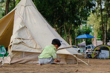 Happy asian boy enjoying with camping tent in beach forest