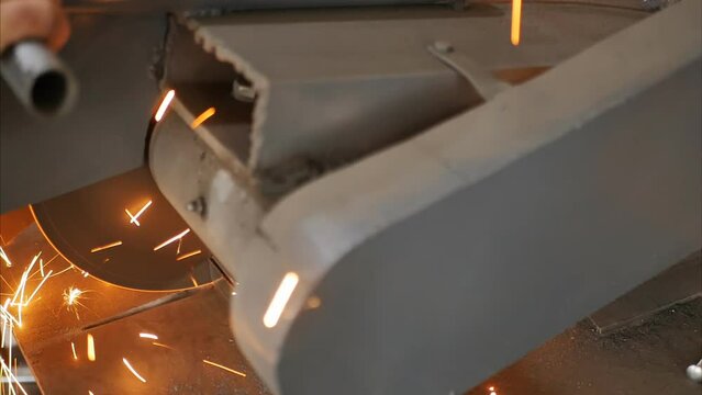 A miter saw cuts metal square tubes into pieces. In the process of cutting iron pipes with an electric industrial miter saw, sparks fly off. Metallurgical industry. Metal structures