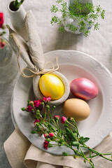 Happy Easter. Stylish easter eggs on a napkin with spring flowers on white wooden background. Table setting. The concept of a happy Easter holiday.