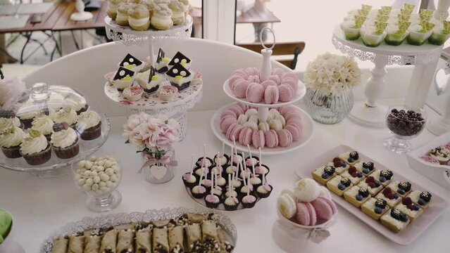 Wedding candy bar, full of goodies. Assorted cakes arranged on white trays.