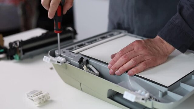 printer repair technician. A male handyman repairs a printer`s scaner 