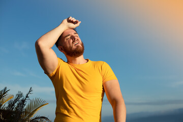 portrait of tired sick exhausted man, handsome guy is suffering from hot Summer heat stroke,...