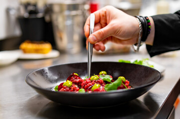 professional chef's hands cooking Raw beef meat tartar in restaurant kitchen