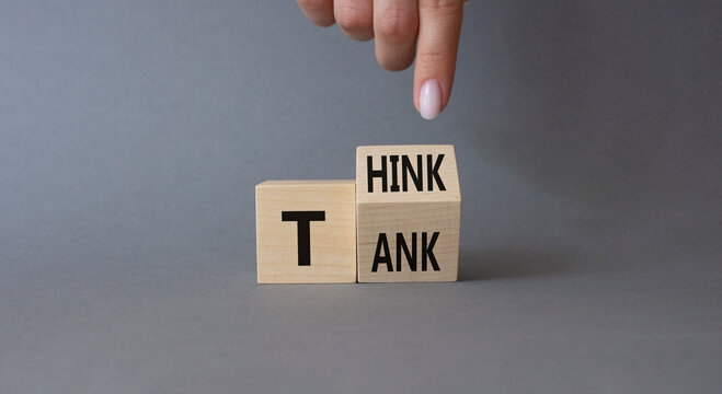 Think Tank symbol. Businessman hand points at turned wooden cubes with words Think Tank. Beautiful grey background. Business and Think Tank concept. Copy space