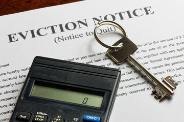 apartment key and calculator on top of the eviction note