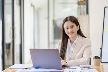 Asian businesswoman working from home and video conference with colleagues working online. With laptop and financial documents, video calling due to social distancing.