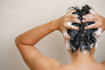 A man is washing his hair with shampoo