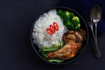 Healthy food grilled chicken has rice and broccoli vegetable in bowl on black wood table.