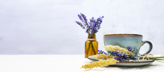 Cup of hot aromatic tea with a bouquet of natural lavender on a gray background. Banner with space...