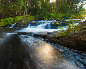 Obraz premium Sun shining below a pool of water at the bottom of a Northern Main waterfall