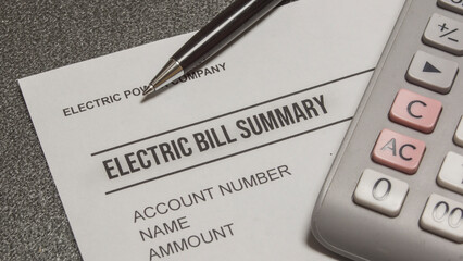 Pen , calculator and  electric bill summary  on the table.