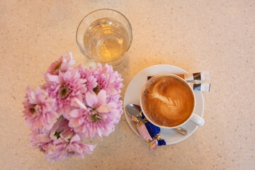 Coffee cup and flowers on the marble background, top view. Still life floral arrangement 