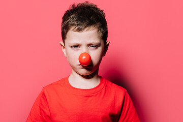 Sad boy in red nose looking at camera