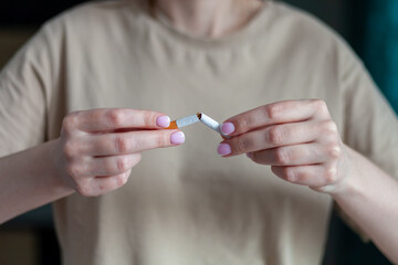 Break a cigarette. A woman breaks a cigarette. Stop smoking cigarettes. Broken cigarette in female hands