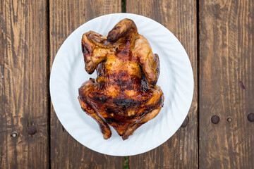 A plate of Lechon Manok, or roasted chicken served outside at a bench.