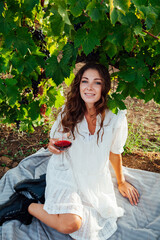 a woman in a white dress with a glass of wine in the vineyard