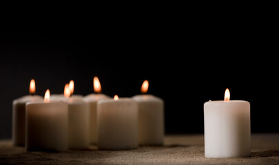 bullying concept, composed by group of lit candles, on sand with black night background