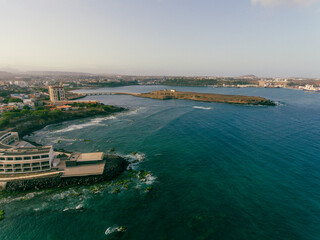 Fototapeta premium Aerial photos of Farol da Praia in Santiago, Cape Verde showcase a stunning lighthouse on a rugged coastline with breathtaking views of the Atlantic Ocean, surrounded by dramatic cliffs, sandy beaches