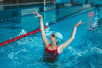 Synchronized girl working out tricks in the pool. Synchronized swimming, sports in the water....